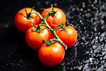 A branch of ripe tomatoes on a wet table. 