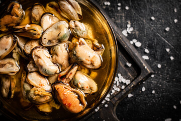 Bowl with pickled mussels on a cutting board. Top view. 