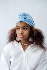 Portrait of young african woman with headscarf and ethnic jewelry. African beautiful brunette curly haired young model