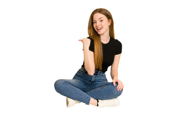 Young redhead woman sitting on the floor cut out isolated points with thumb finger away, laughing and carefree.