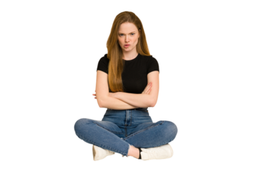 Young redhead woman sitting on the floor cut out isolated frowning face in displeasure, keeps arms folded.