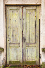 Old green wooden door as the entrance to ruined abandoned house