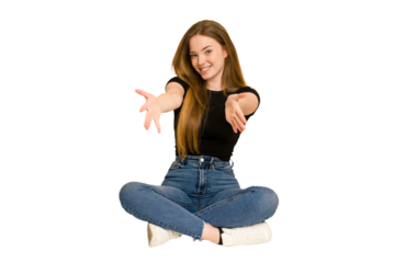 Young redhead woman sitting on the floor cut out isolated showing a welcome expression.