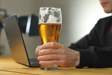 person holding a beer mug next to a laptop