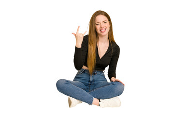 Young redhead woman sitting on the floor cut out isolated showing thumbs up and thumbs down,...