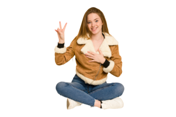 Young redhead woman sitting on the floor cut out isolated thinking and looking up, being reflective, contemplating, having a fantasy.