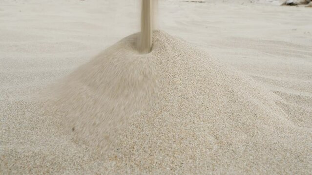 Sand falling onto pile on beach. Falling sand forms a pile
