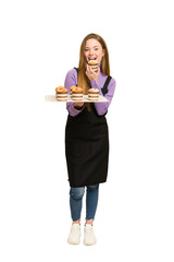 Full body of a young redhead woman  holding a recently made muffins cut out isolated