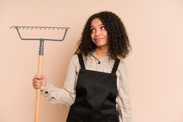 Young african american gardener woman holding a rake isolated dreaming of achieving goals and purposes