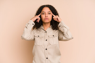 Young african american curly woman isolated focused on a task, keeping forefingers pointing head.