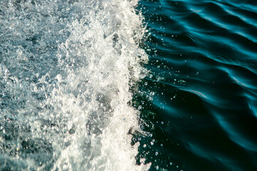 Waves on the sandy beach. Water background, blue sea water. Beautiful texture of sun glare on the...