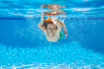 Kid swimming in pool underwater. Child boy swim under water in sea.