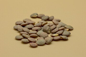 Green lentils in a top view with an orange background.