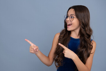 Wow, it's unbelievable. Shocked teenager child pointing aside at copy space. Teen girl pointing with two hands and fingers to the side. Happy girl face, positive and smiling emotions.