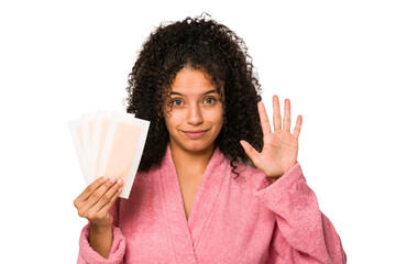 Young african american curly woman holding an hair removal bands isolated smiling cheerful showing...