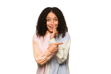 Young african american curly woman isolated saying a gossip, pointing to side reporting something.