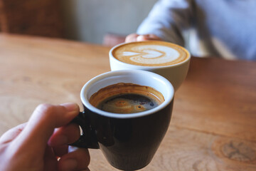 Closeup image of a couple people clinking coffee cups together in cafe