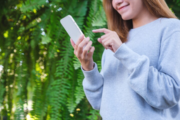 Portrait image of a woman holding and using mobile phone in the outdoors