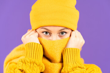 Portrait of winter clothing woman looking at camera isolated on purple background