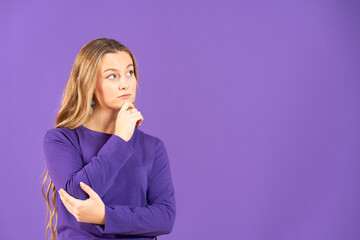 Young caucasian woman thinking and looking at copy space isolated on purple background