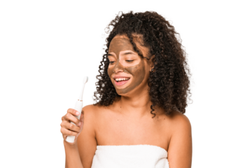 Young african american woman toothbrushing and applying herself a facial mask isolated
