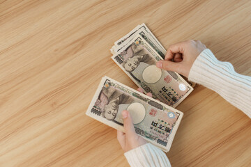Woman hand counting Japanese Yen banknote over table background. Thousand Yen money. Japan cash,...