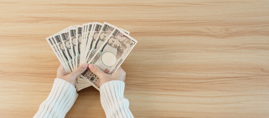 Woman hand counting Japanese Yen banknote over table background. Thousand Yen money. Japan cash, Tax, Recession Economy, Inflation, Investment, finance, savings, salary and payment concepts