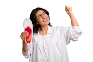 Young indian chiropodist woman holding a insoles for shoes cut out isolated raising fist after a victory, winner concept.