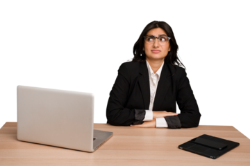 Young indian woman in a table with a laptop and tablet isolated confused, feels doubtful and unsure.