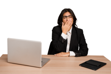 Young indian woman in a table with a laptop and tablet isolated yawning showing a tired gesture covering mouth with hand.