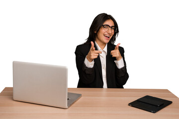 Young indian woman in a table with a laptop and tablet isolated pointing to front with fingers.