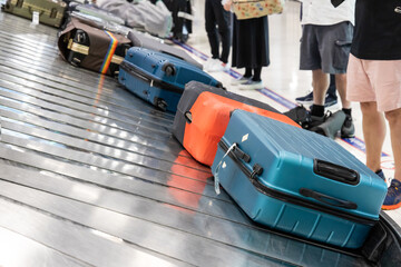Baggage luggage at airport arrival carousel with passengers awiating to claim theirs