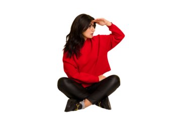 Young indian woman sitting on the floor cut out isolated looking far away keeping hand on forehead.