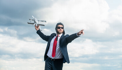 businessperson in suit and pilot hat launch plane toy on sky background