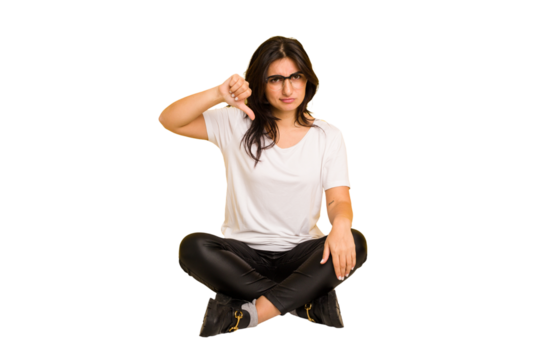 Young indian woman sitting on the floor cut out isolated showing thumb down, disappointment concept.