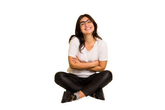 Young indian woman sitting on the floor cut out isolated laughing and having fun.