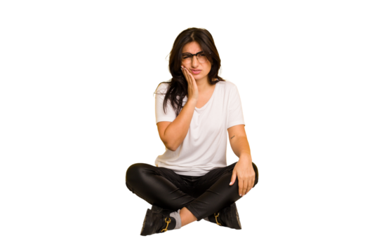 Young indian woman sitting on the floor cut out isolated having a strong teeth pain, molar ache.