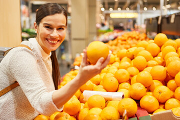 Glückliche Kundin im Supermarkt kauft frische Orangen