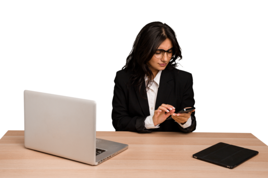 Young indian woman in a table with a laptop and tablet using a mobile phone isolated