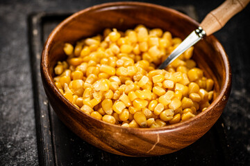 Canned corn on a wooden plate.