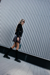 glamorous lady with long legs in a black jacket walking on the street