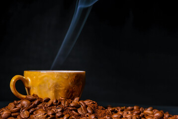 Coffee cup among coffee beans on a black background.