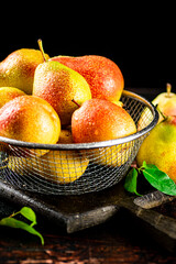 Pears in a colander on a cutting board. 