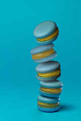 blue macarons on a blue background folded in a pyramid. air dessert with blueberries