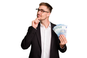 Young business caucasian man holding euro banknotes isolated cut out looking sideways with doubtful and skeptical expression.