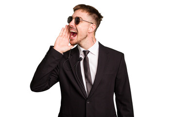 Security bodyguard man wearing a suit isolated cut out shouting and holding palm near opened mouth.