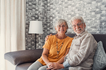 Beautiful hoary good-looking mature spouses relaxing together on comfy couch at modern home smiling staring at camera feel carefree. Good harmonic relationships, happy marriage, endless love concept.