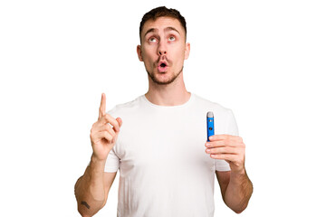 Young caucasian man holding a vaporizer cut out isolated pointing upside with opened mouth.