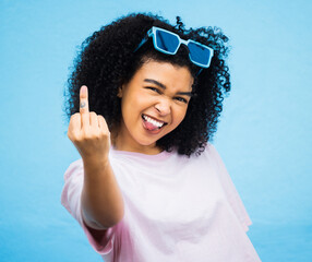 Portrait, middle finger and hand, emoji and black woman in studio, rude and carefree on a blue...