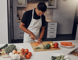 Cooking, food and vegetables with a man cutting ingredients in the kitchen on a wooden chopping...